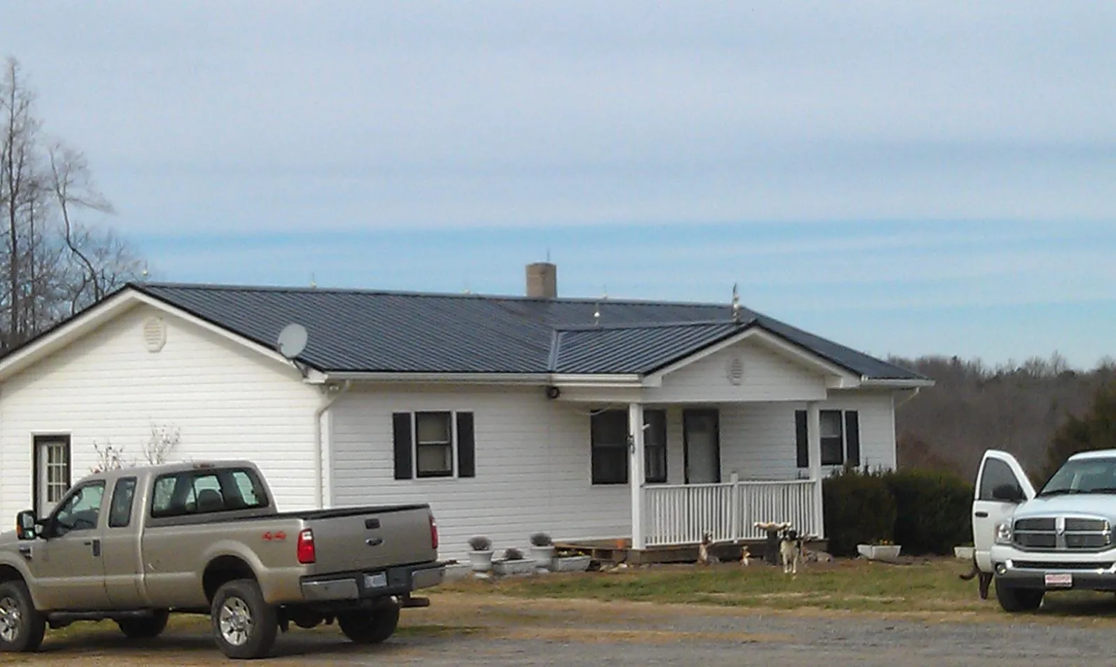 Finished dark metal roof on a white ranch home with work trucks parked in Santa Ysabel