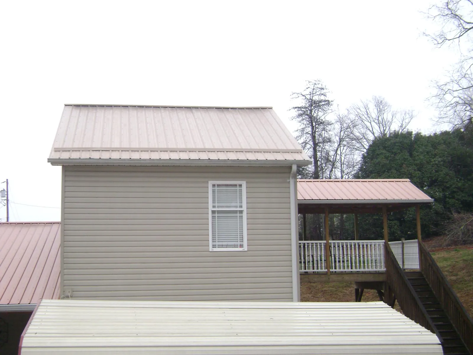 Tan metal roofs on a two story addition and attached porch, from a Roof Replacement job in Santa Ysabel
